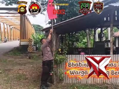 Bhabinkamtibmas Bantu warga pasangkan bendera